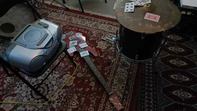 bass guitar, floortom, and cassette player, scattered playing cards