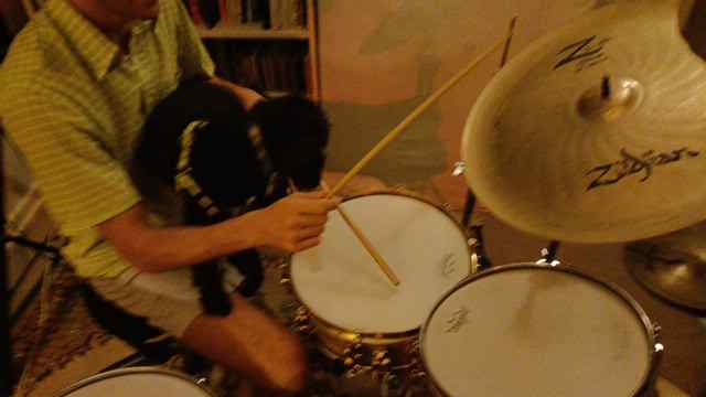 Andrew playing drums with Roxi (black dog) on his lap.