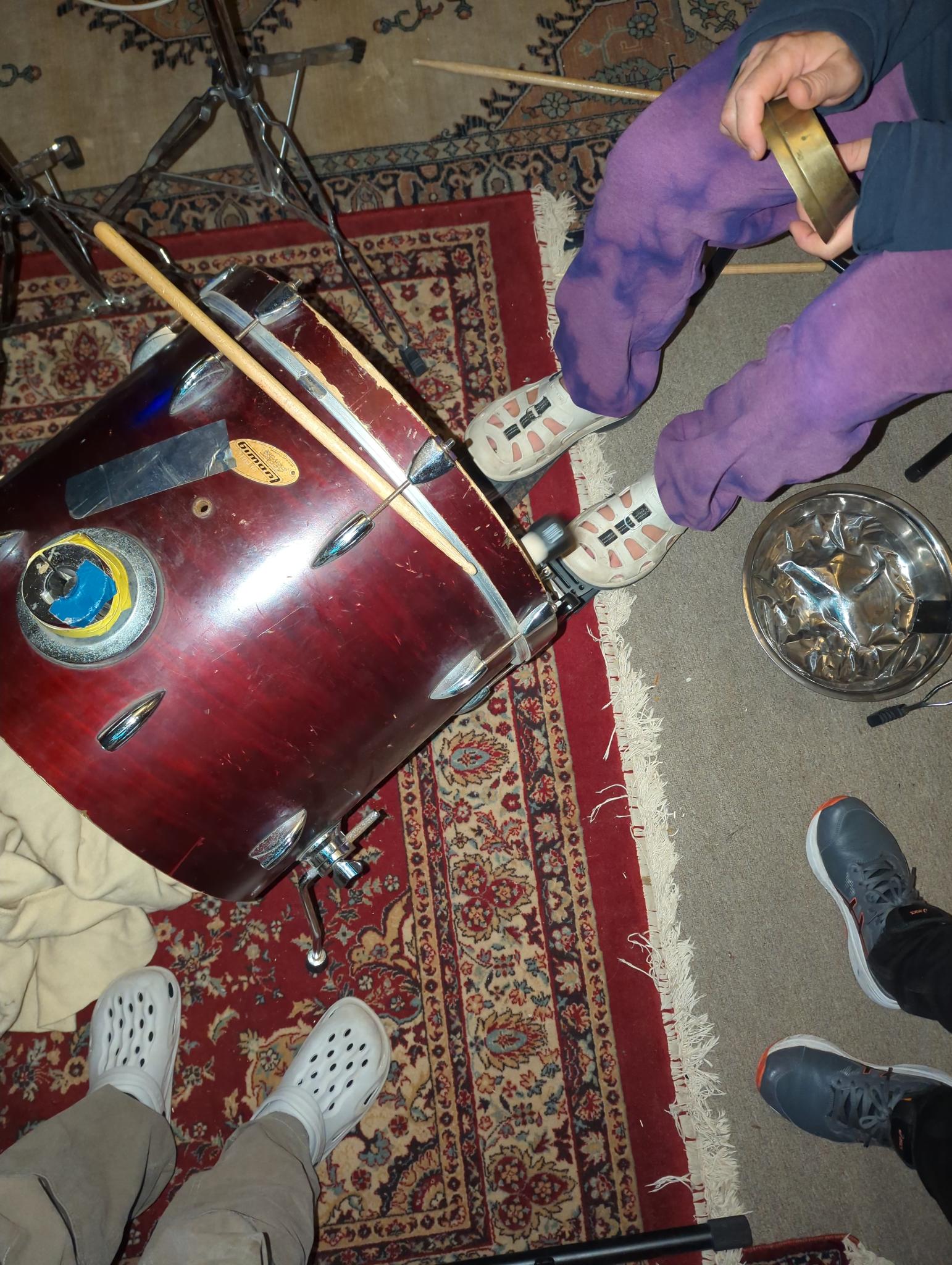 downward shot of people playing drums, focusing on peoples' feet and percussion instruments on floor